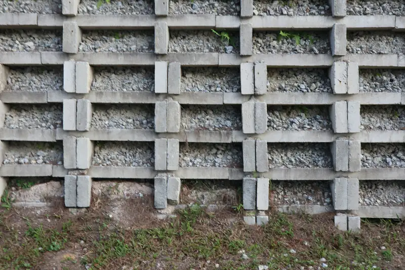 Modular concrete crib-style retaining wall with gravel fill, built into a grassy slope